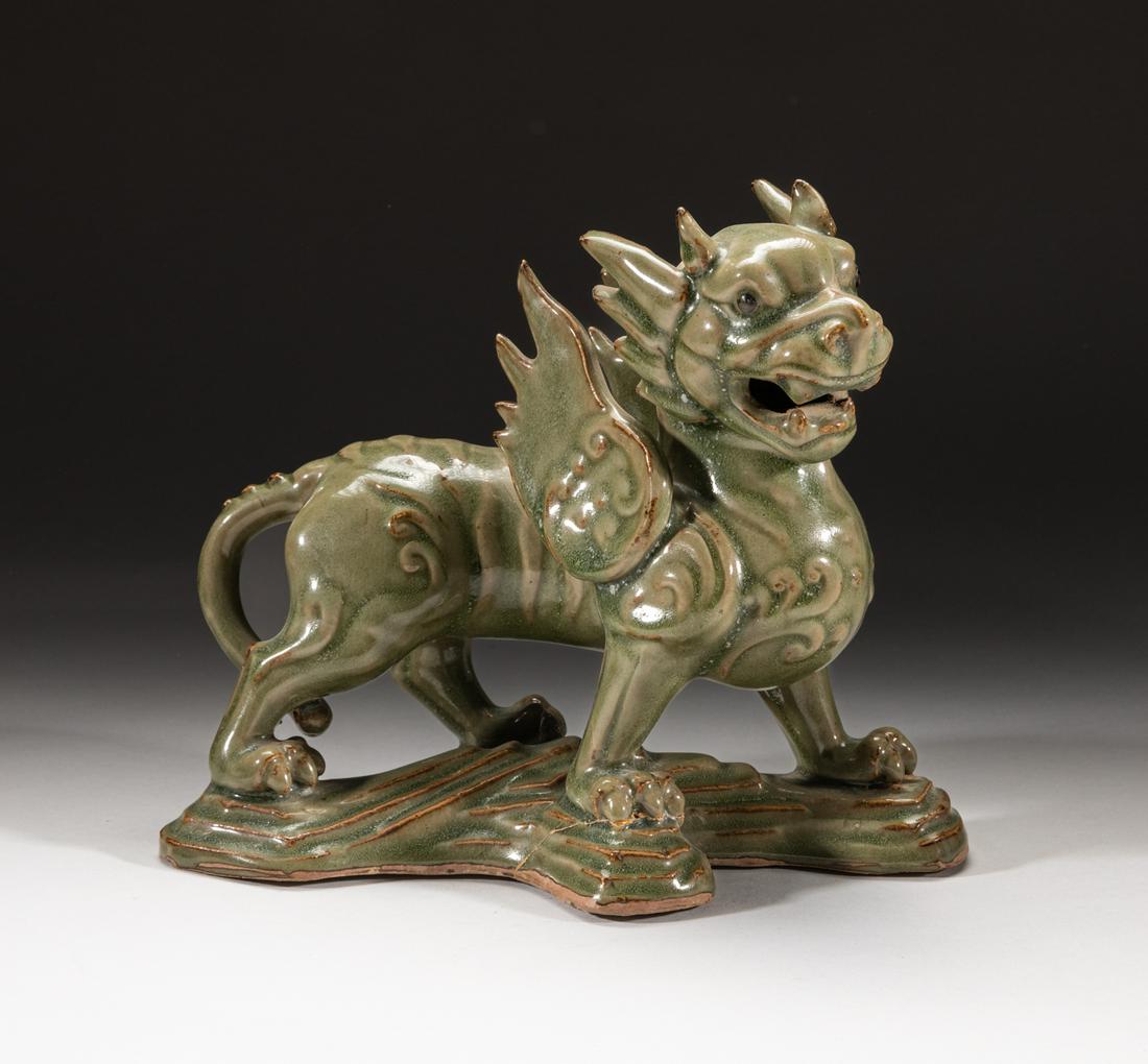 Important Korean Porcelain Table Sculpture: The powerfully modeled beast striding to the left with head raised and jaws open baring its teeth, set with a pair of upright flame-shaped wings, the three-clawed paws standing on a cross type stand, 