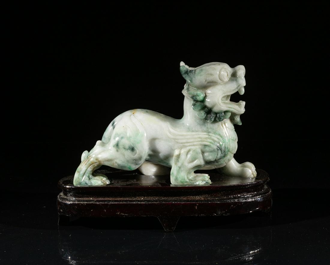 Large Chinese Jade Jadeite Beast Table Sculpture: Skillfully carved as a ferocious beast standing on a fitted wood base, the head looking forwards and the open mouth revealing its teeth, nicely incised beard and mane, the right two paws extending for