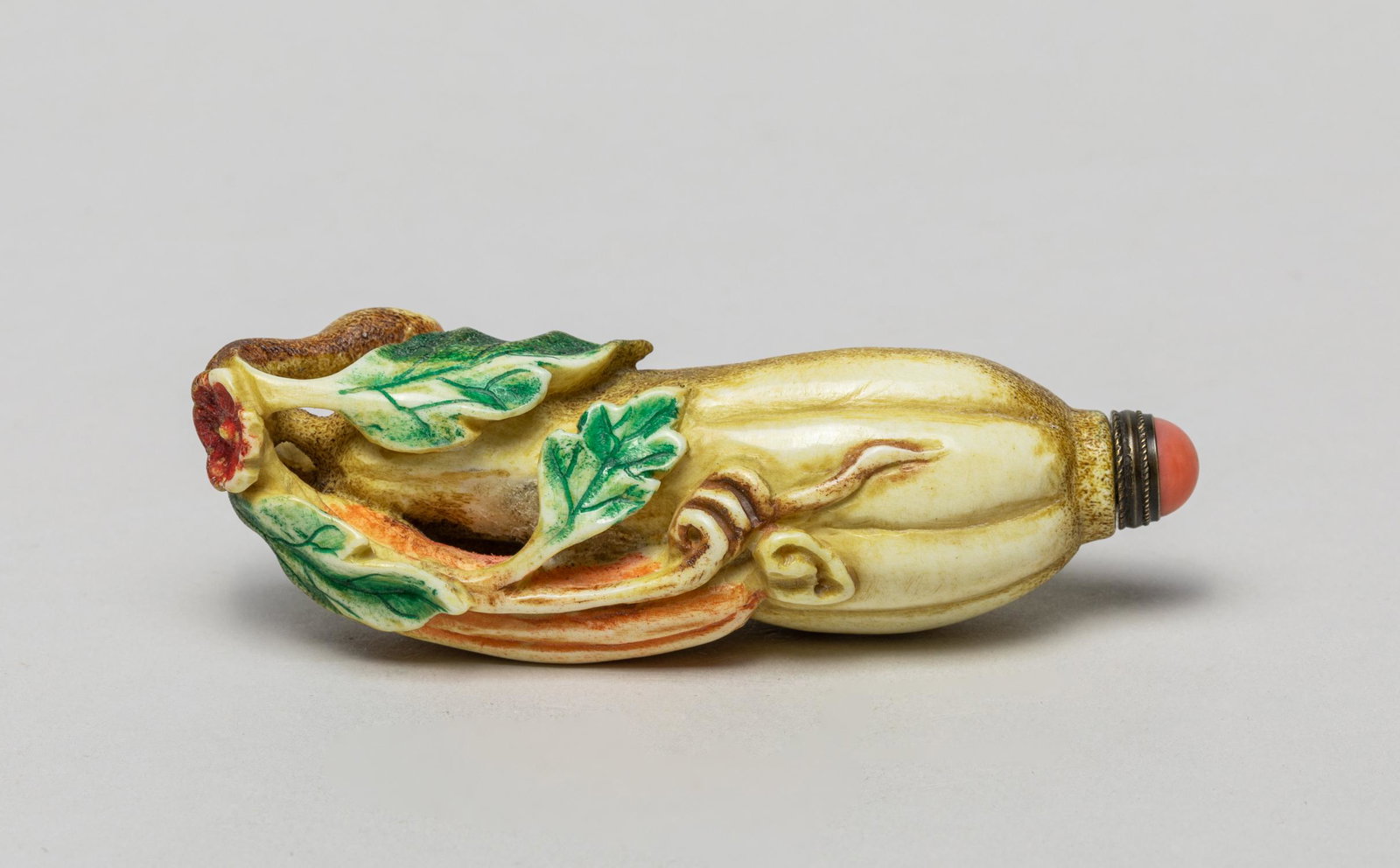 Vintage Chinese Bone Like Snuff Bottle, Fruit: Skillfully carved in elongated fruit form, borne on a gnarled stem issuing flowers, leaves and a smaller attendant fruit, with a coral like stopper. 2.55inch L, 1.05inch W.