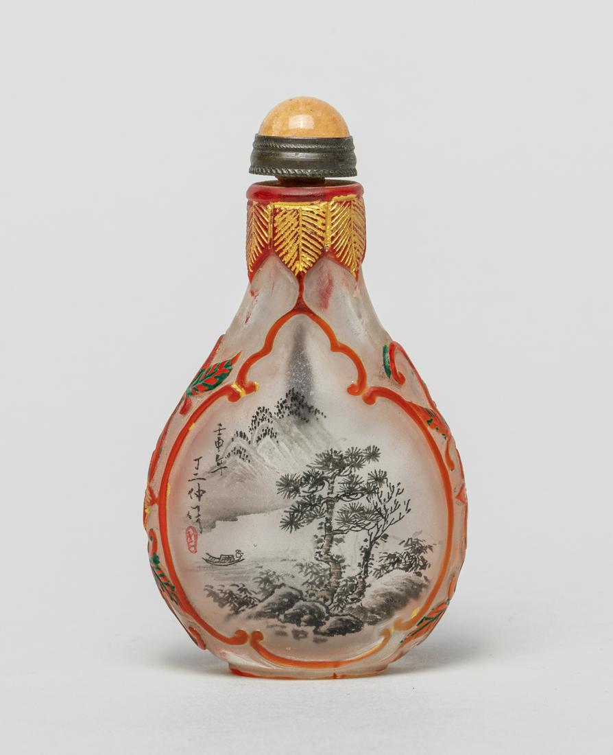 Chinese Inside Painted Snuff Bottle: Of flattened pear shape, the inside painted with mountainous river landscape to either side with inscription, the exterior with red glass design of stylized panels enclosing the interior landscape div