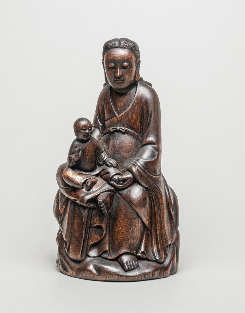 Vintage Chinese Agarwood Kuanyin: Collectible agarwood carved Kuanyin sculpture, the seated Kuanyin dressed in long, flowing robes, with a boy sitting on her right bending leg, the serene face with downcast eyes, a pronounced nose and