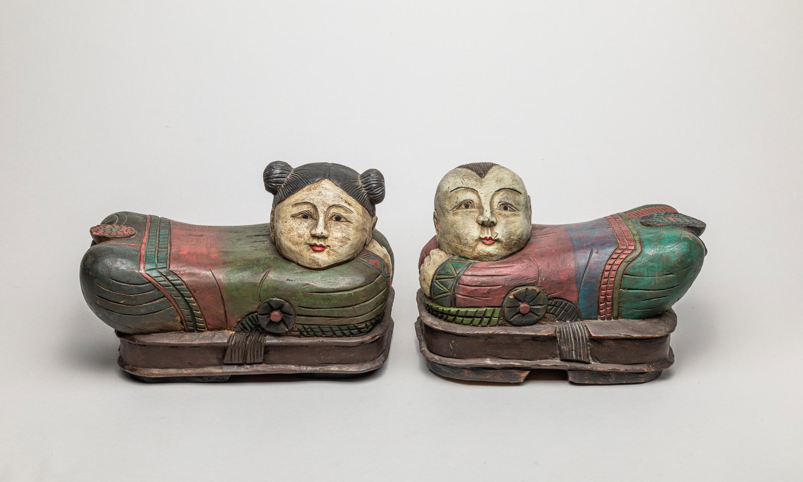 Pair Chinese Wood Carved Children Pillows: Each carved in the form of a youth detailed with crouching body and facial features, the haunch carved with a lotus seedpod, 8.5inch H, 12.6inch L, 7inch W (larger).