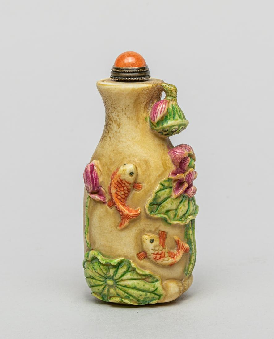 Chinese Bone Like Snuff Bottle: Modeled in vase form, carved in high relief with a pair of fish and lotus, a lotus seedpod extending at the rim, with stopper. 3.15inch H, 1.45inch W.
