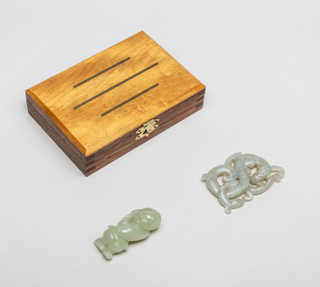 Collectible Chinese Jade Carvings: Including a pale celadon carved boy holding a leafy branch, the face with laughing expression, and a grayish white jade carved and pierced with archaistic dragon and phoenix, the sinuous bodies interl