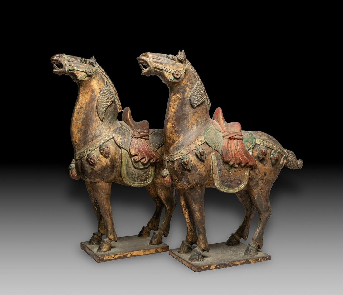 Pair Large Chinese Wood Horses: A pair of collectible large wood horse sculptures, carved standing foursquare on a rectangular base, with finely incised mane, tail and hooves, with a textured red saddle and green rug. Approx. 26inch