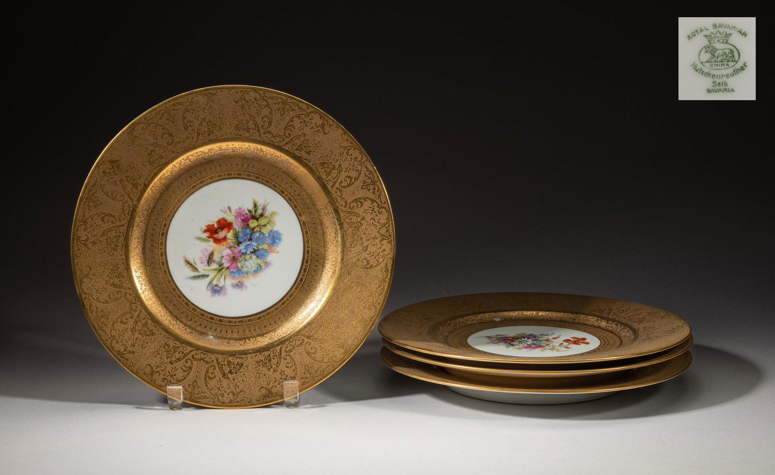 Continent Gold & Famille Rose Porcelain Plates: Set of four vintage German type porcelain plates, the interior centre painted with various blossoming flowers, the sides decorated with elaborate foliage pattern in gold coloring, each base marked Hut