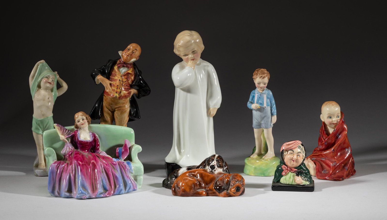 Rare Royal Doulton Porcelain Figures: Group of 8 glazed porcelain table sculptures, modeled in the form of a boy in a white robe, a gentleman, a shirtless boy, two crouching dogs, a boy in carpet, a boy with flowers, or a lady on sofa, ea