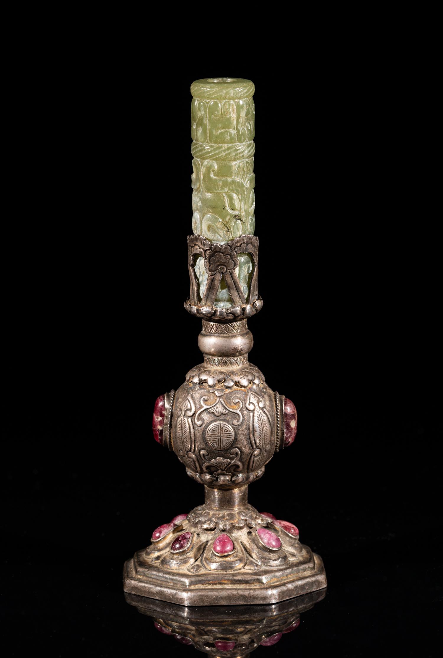 Chinese Jade & Silver Hat Final: The globular body rising from a splayed foot to a cylindrical neck, carved with leaves, stylized symbols and lotus petals, inlaid with purple-red gemstones, supporting a jade tubular carving, carved w