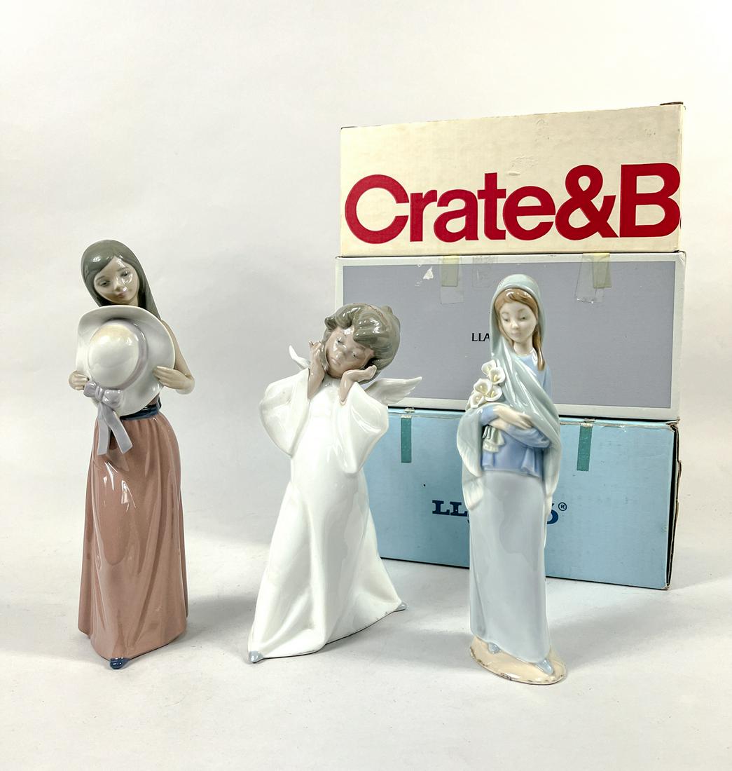 Collectible Lladro Porcelain Figures: Group of three Lladro porcelain figure sculptures, moulded as a lady holding flowers, a lady holding a hat or a child wearing white robes with wings, each base marked Llladro Hand Made in Spain. 9.9in