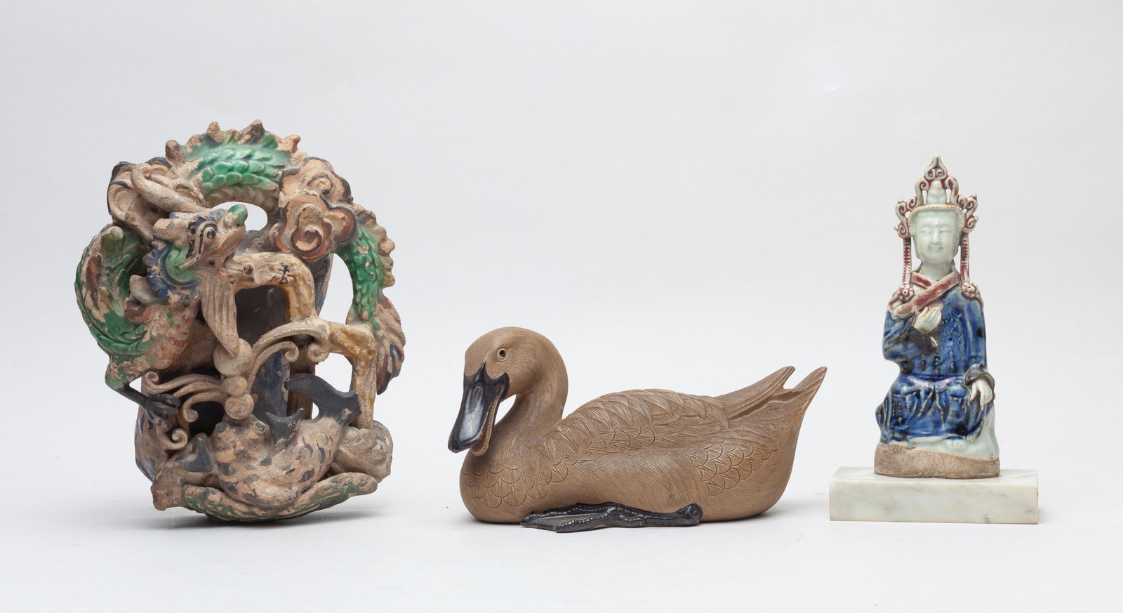 Set Chinese Porcelain Sculptures: Three pieces as a group, one moulded as seated Buddha, one as a duck with its head turned to the right, the other as a wall hanging vase carved in openwork with a ferocious drawings above waves. 8.2in