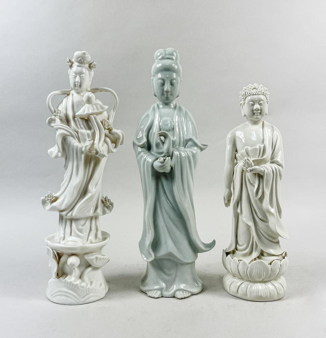 Chinese Export Blank De Porcelain Figures: Three collectible blank de standing porcelain figures, each dressed in a long flowing robe with hands holding a lotus stem, a lotus bloom or a bottle, the face with meditative expression framed by pen