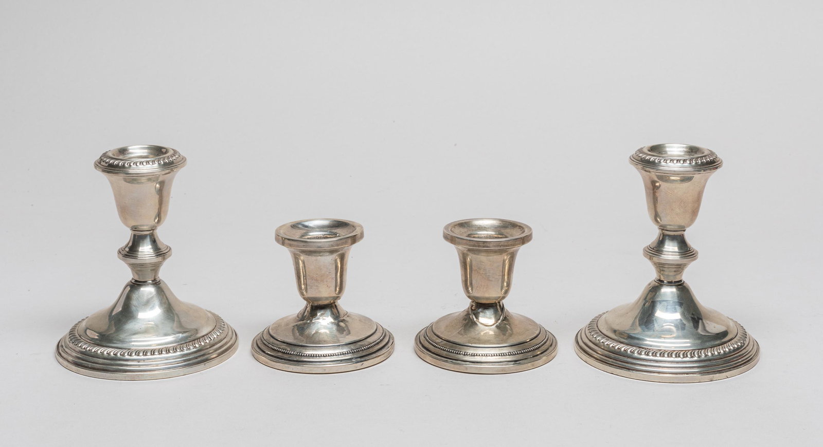 Group Sterling/Cerment Filled Candle Sticks: Group of four sterling candlestick holders, two base marked empire Sterling Weighted, two mark Sterling Cement Filled Reinforced With Rod. 4.2inch H, 3.8inch W (largest).