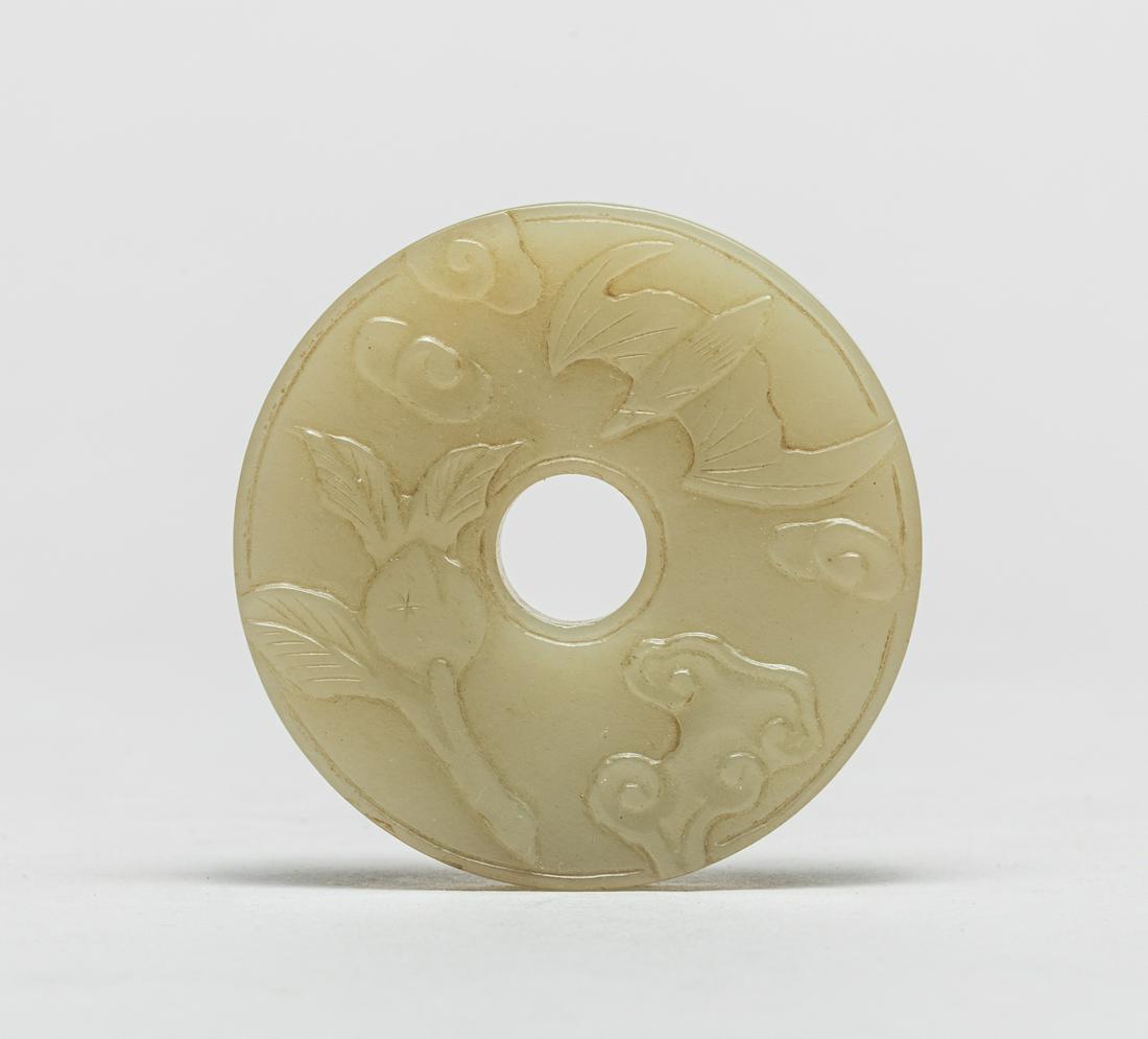 Chinese Jade Carved Bi: Of circular form pierced with a central aperture, carved to one side with peach, lingzhi, a bat and clouds, the reverse with archaic scrolls, the stone in an even place celadon tone. 2.17inch W.