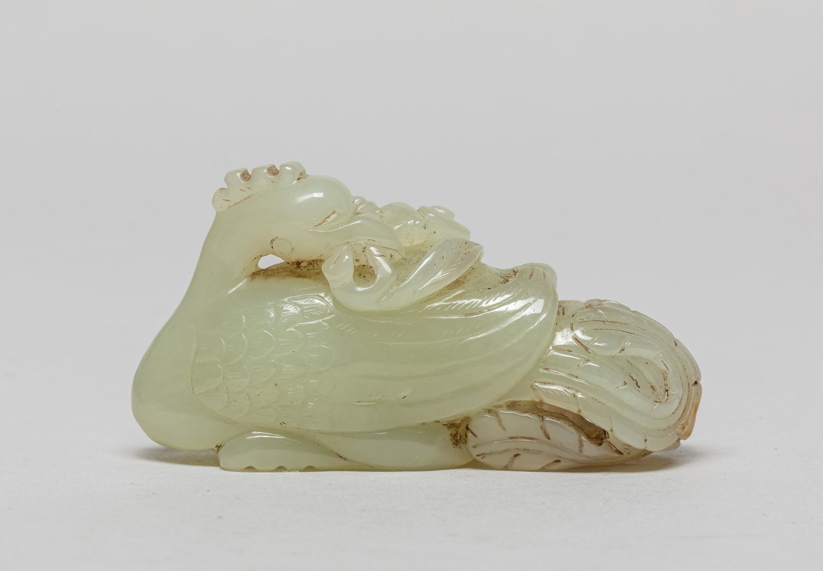 Rare Chinese Jade Carved Goose: Carved in the form of a goose with Its head turned sharply backwards and grasping a leafy lingzhi branch, the white stone with faint russet inclusions at the intertwined openwork tails. 1.55inch H, 3.