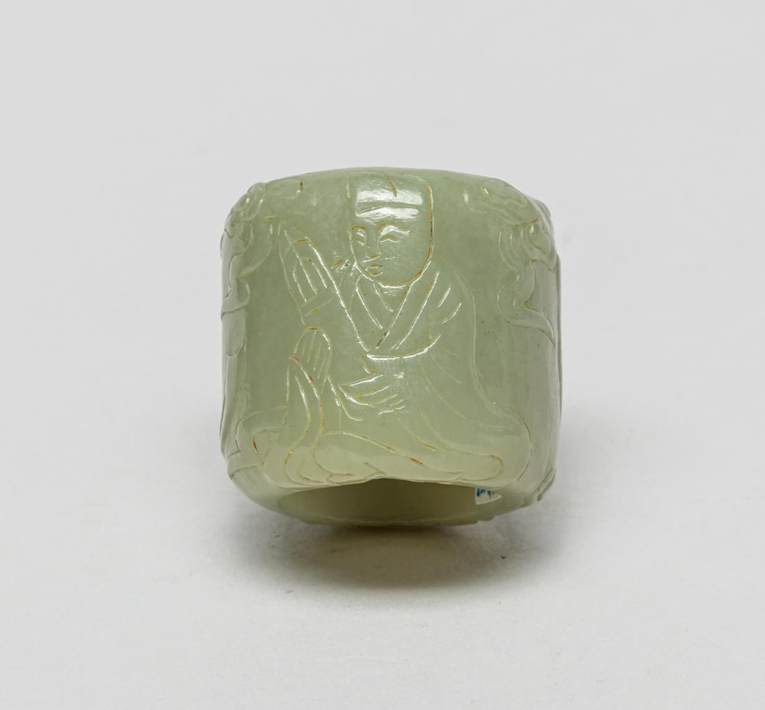 Chinese Pale Yellow Jade Thumb Ring: Pale yellow celadon jade thumb ring, the exterior carved in low relief with a male playing an instrument and a female dancing and swinging ribbons. 1.43inch W, 1.3inch H.