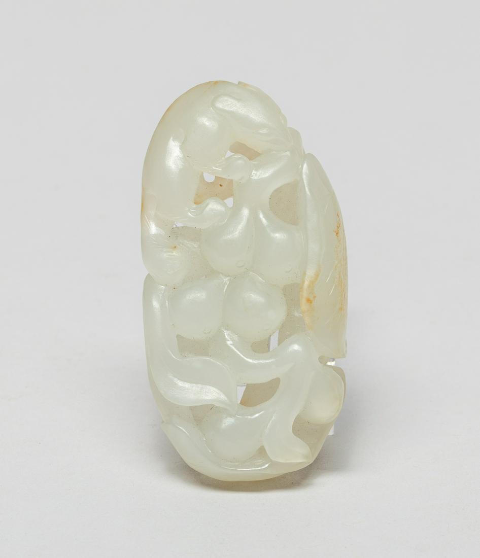 Chinese Russet Jade Carving: The lustrous and smoothly polished white stone finely worked with a squirrel clambering on a cluster of grapes borne on a gnarled stem further issuing attendant large leaves, with faint russet inclusi
