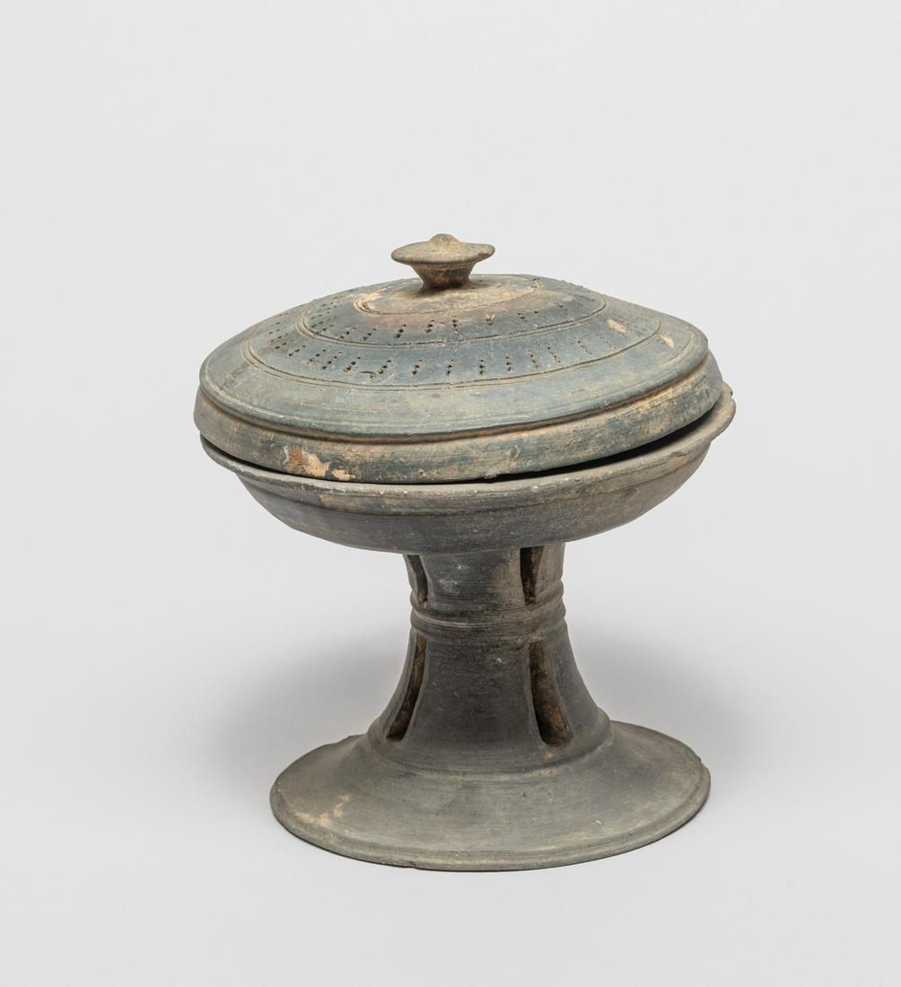 Korean Joseon Pottery Tall Vase: Korean early Joseon carved pottery piece, the hollow waisted body rising from a splayed foot and supporting a shallow bowl, the cover pierced with with well-arranged apertures. 6.5 inch H; 6 inch W.