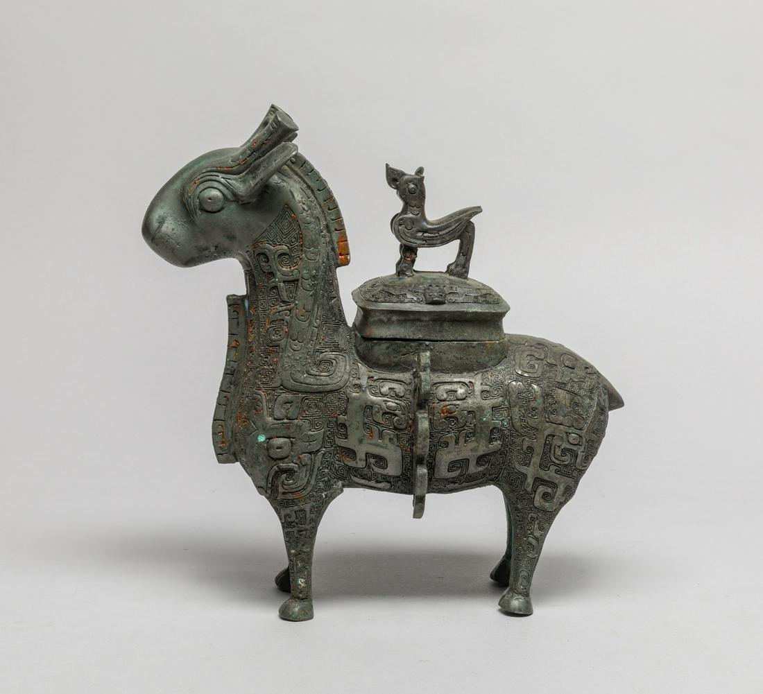 Korean Early Bronze Horse Covered Pot: Modeled standing foursquare with the head looking forwards, detailed with bulging eyes and upright horns and ears, the body cast with taotie masks on a leiwen ground, flanked by a pair of raised flang