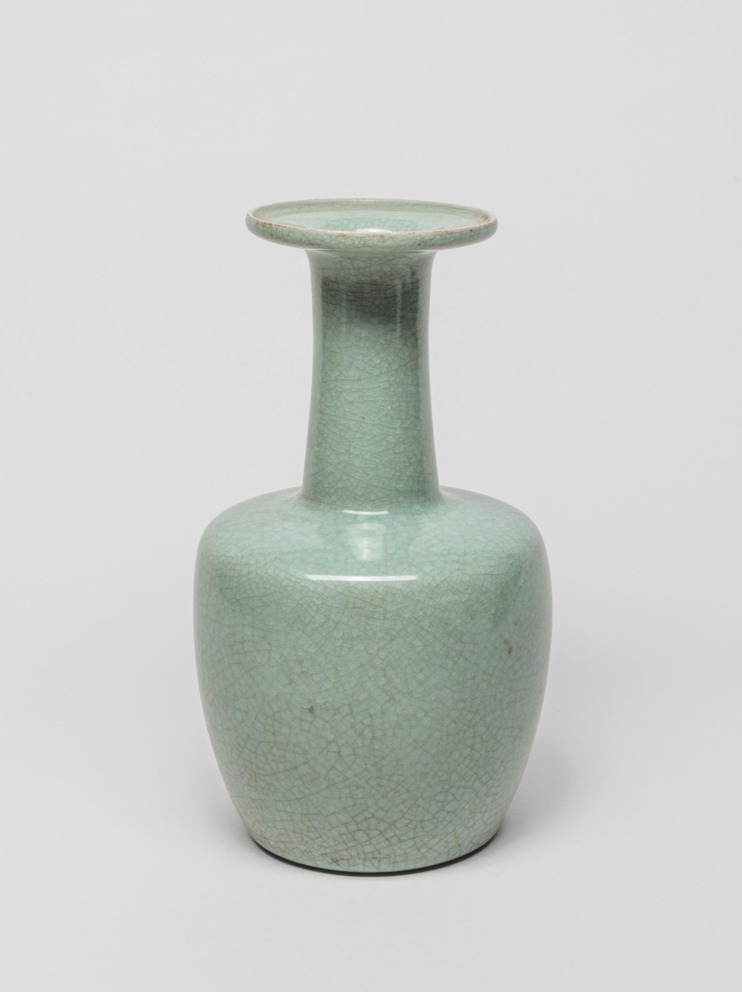 Chinese Celadon Glazed Porcelain Vase: The ovoid body rising to an angled shoulder and gently waisted neck with dished rim, covered the inside and out with a celadon glaze suffused with a matrix of natural crackles. 9 inch H; 5 inch W.
