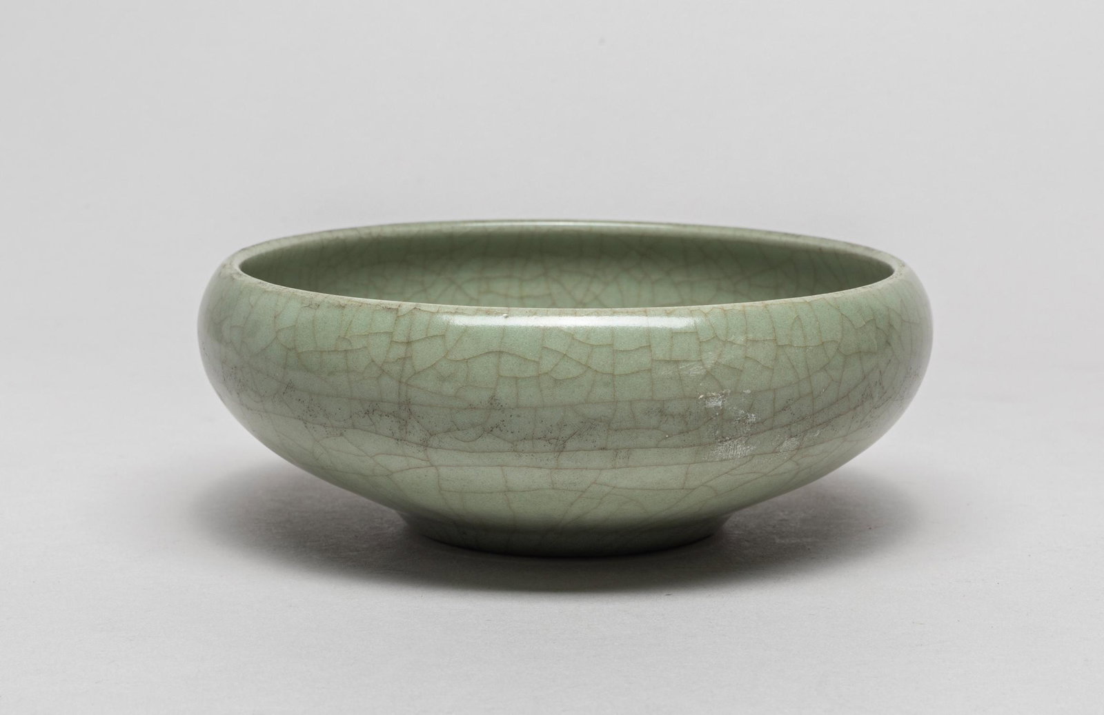 Chinese Ru Type Porcelain Brush Washer: The compressed globular body rising from a short tapering foot, covered overall with an even celadon glaze suffused with network of brown crackles save for the foot. 5.65inch W, 2.1inch H.