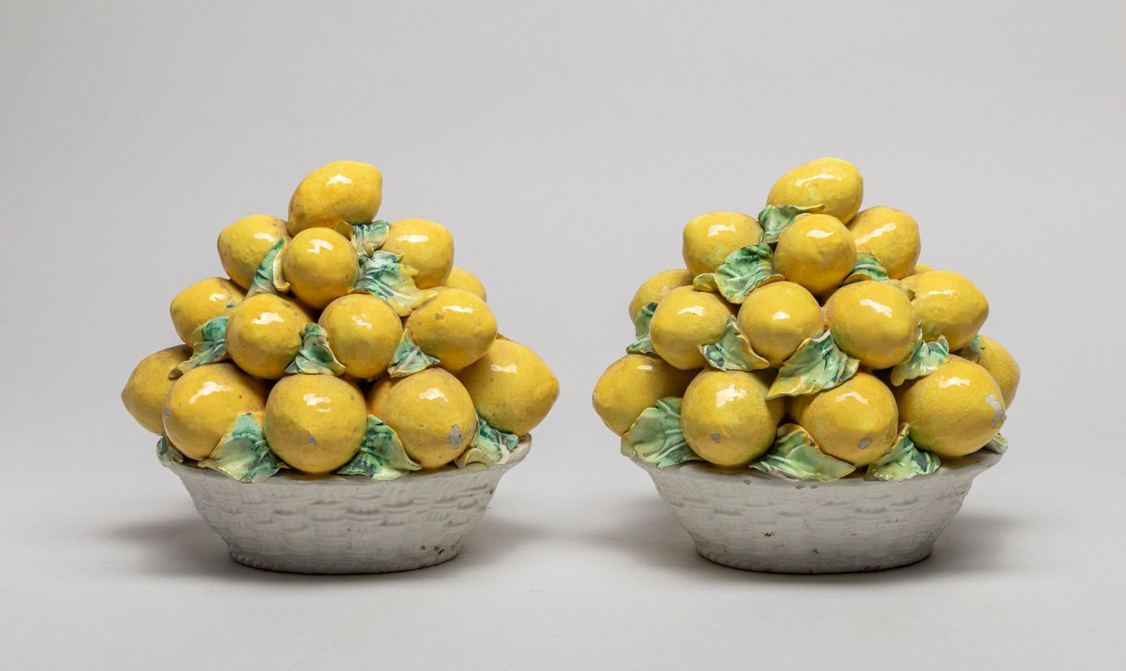 Two Italy Porcelain Table Fruit Sculpture: Modeled in the form of a basket of lemons with leaves, the base marked Italy. 6.7inch H, 7.3inch L, 6.2inch W (larger).