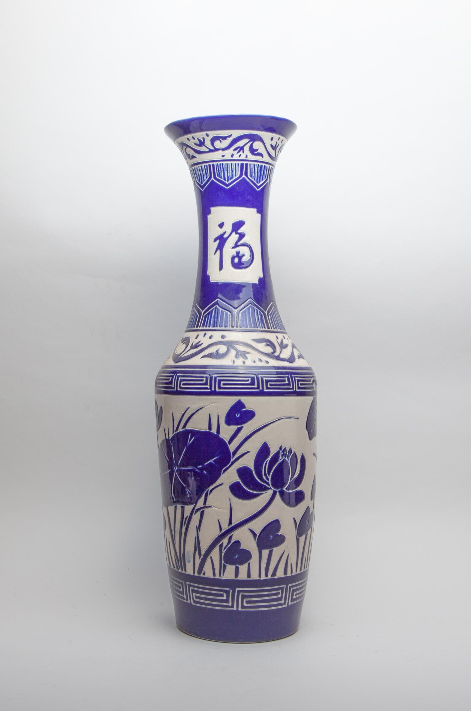 Tall Korean Porcelain Garden Vase: The baluster body rising to a tall waisted neck with flared rim, carved with lotus between fret borders beneath three character panels at the neck, glazed in creamy white and cobalt blue colors. 24.6i
