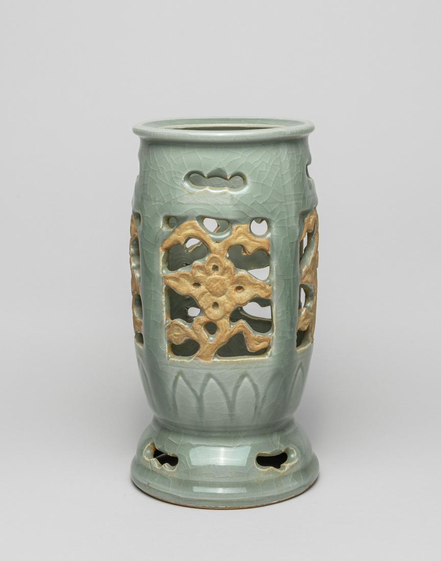 Korean Celadon Glazed Porcelain Vase: The ovoid body carved in openwork with four panels of stylized flowers, above a band of upright petals, the mouth and foot with openwork stylized shapes, covered overall with a soft celadon glaze suff