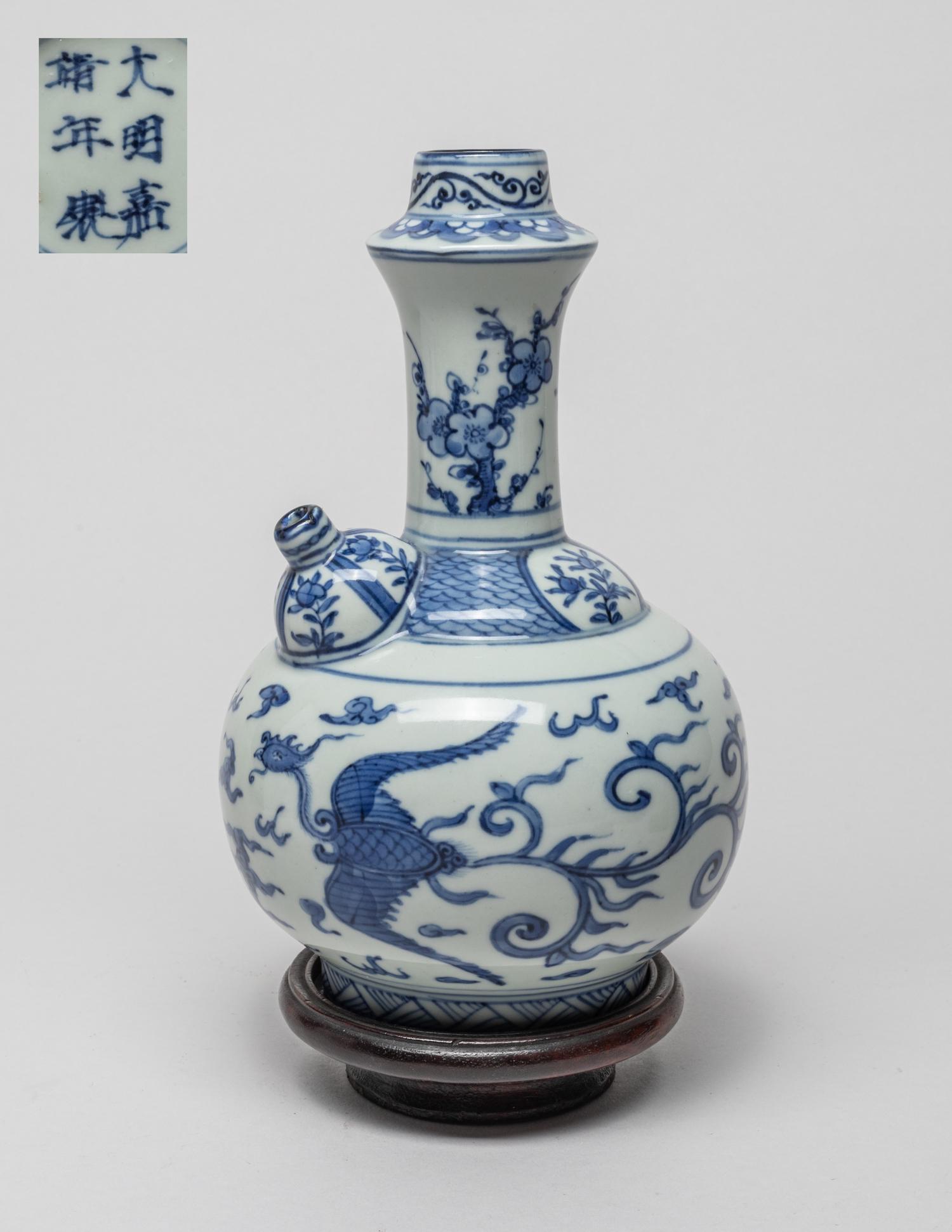 Chinese Temple Used Porcelain Kendi: The globular body painted with a pair of phoenixes amidst flames and clouds, the neck with plum blossoms, the bottom marked with six characters enclosed in double circles, with a wood stand. 7.6inch H