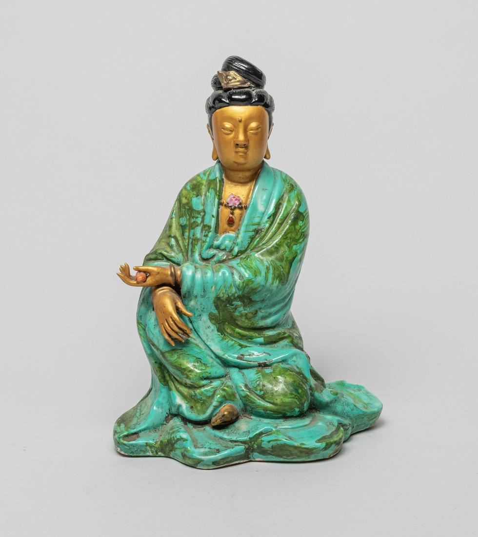Chinese Turquoise Glazed Porcelain Figure: The hollow porcelain seated figure wearing a long flowing robe glazed in turquoise and green colors, the left hand holding a scroll and right hand resting on knee, the face glazed golden color with a 