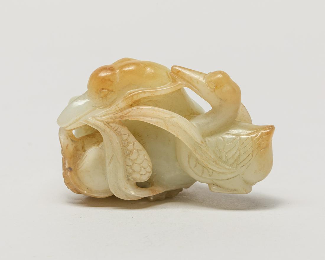 Chinese Russet Jade Goose: Naturalistically carved in openwork as a duck and two young ducks grasping leafy stems, the legs tucked beneath the body, the stone in pale celadon stone with russet inclusions. 2.7inch L, 1,75inch W,