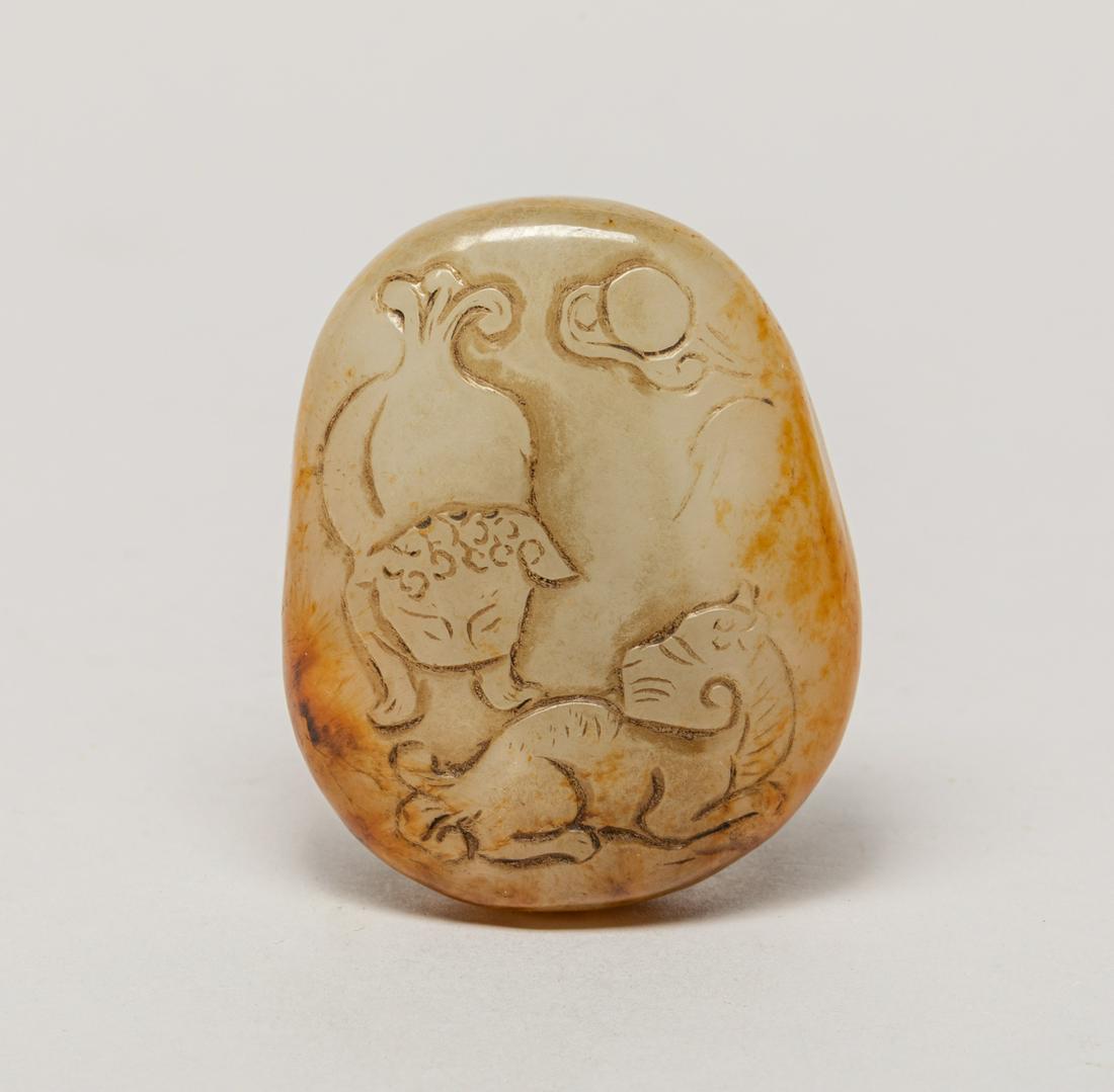Chinese Russet Jade Carving: The pebble-shaped russet jade carving carved on one side with two foo dogs and the reverse with a pine tree, a pavilion and lingzhi. 2.05inch L, 1.67inch W.