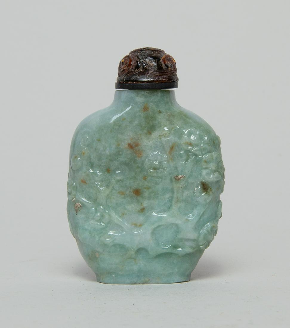 Chinese Jade Jadeite Snuff Bottle: Of flattened spade form, carved with plum blossom branch in relief, of pale green one with russet and green suffusions, with a stopper carved with a shou character and scrolls. 2.6inch H, 1.7inch W.