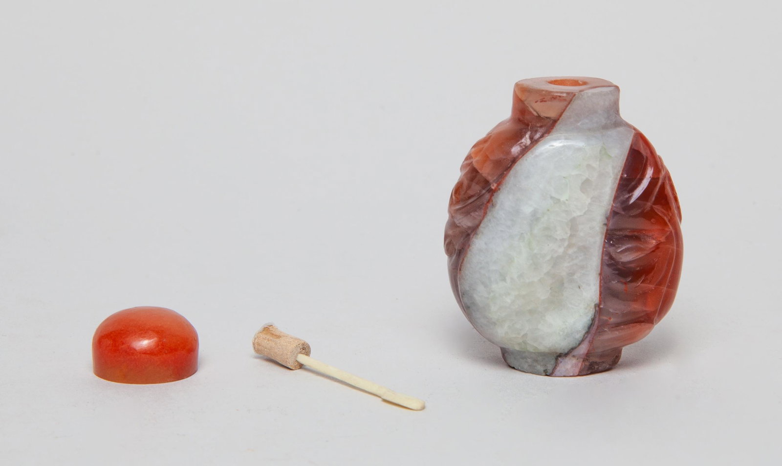 Rare Chinese Cameo Agate Snuff Bottle: Of spade form, one side carved with a bird and bamboo, the reverse with a dragonfly and leafy stem, the stone in red and white colors, with a matched stopper. 2.55inch H, 1.7inch L, 1.05inch W.