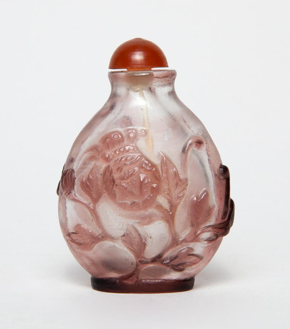 Chinese Overlay Glass Snuff Bottle: Of rounded form, one side carved with a pair of bats around peaches, the reverse with a butterfly and flowers, in light purple color on a clear ground, with a matched stopper. 2.75inch H, 1.95inch W.