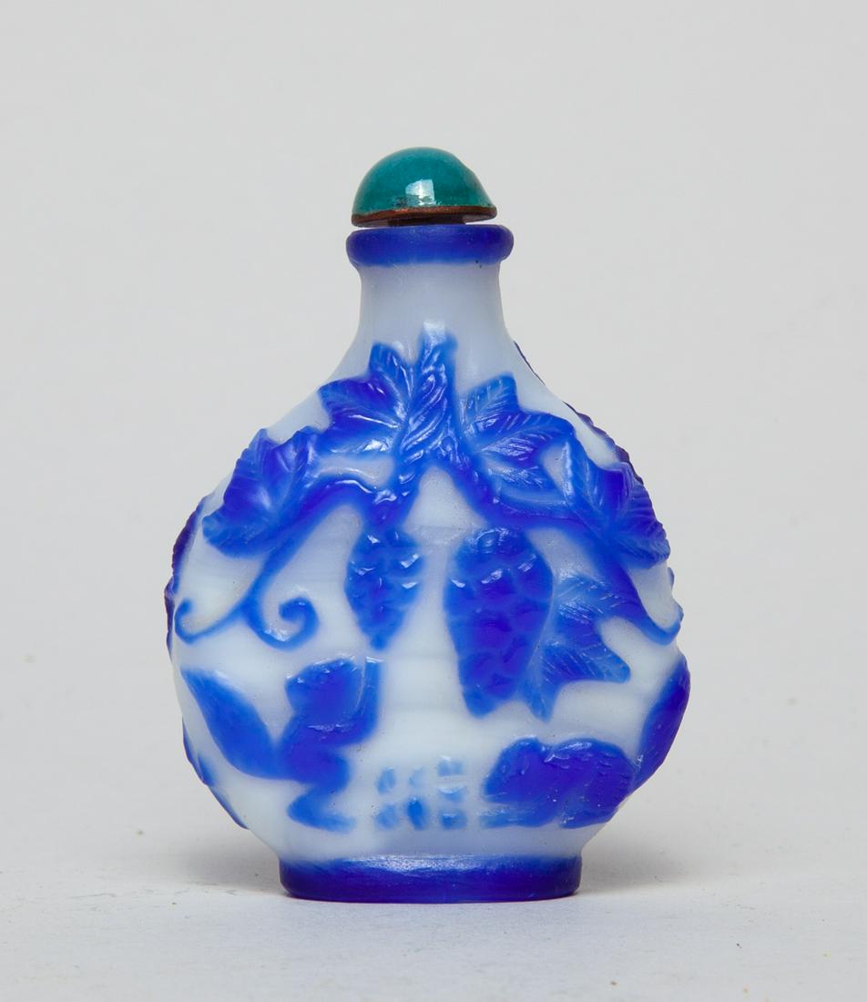 Chinese Overlay Glass Snuff Bottle: Of rounded form, with design of squirrels amid meandering vines issuing pine cones and leaves on either side, in blue on a milky-glass ground, with a turquoise glazed porcelain stopper. 2.6inch H, 1.8