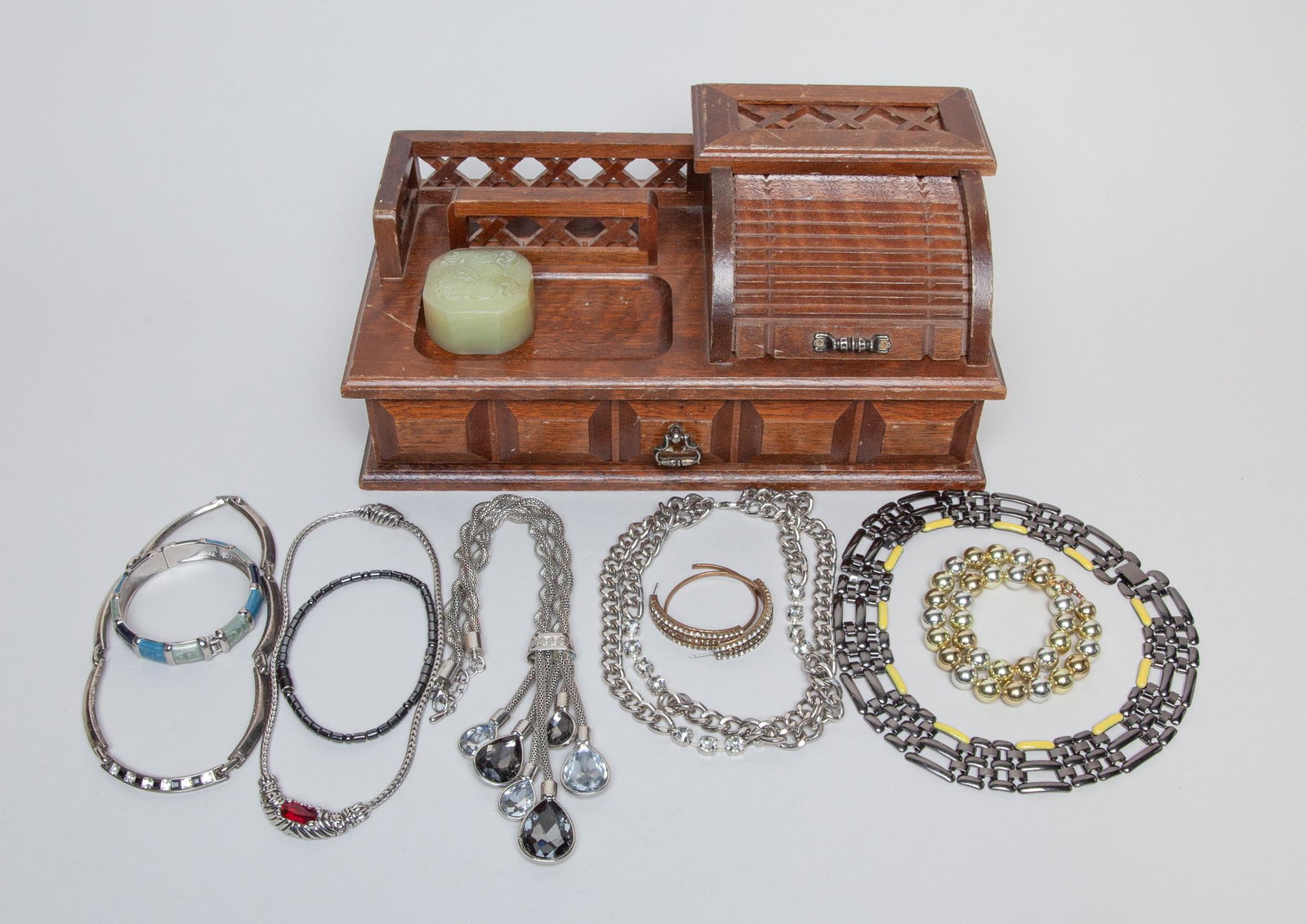 Lot of Costume Jewelry: Including 6 necklaces, 2 bracelets and a pair of earrings, with a wood jewelry box decorated with a stone knob carved with a beast. 20inch L (largest necklace).