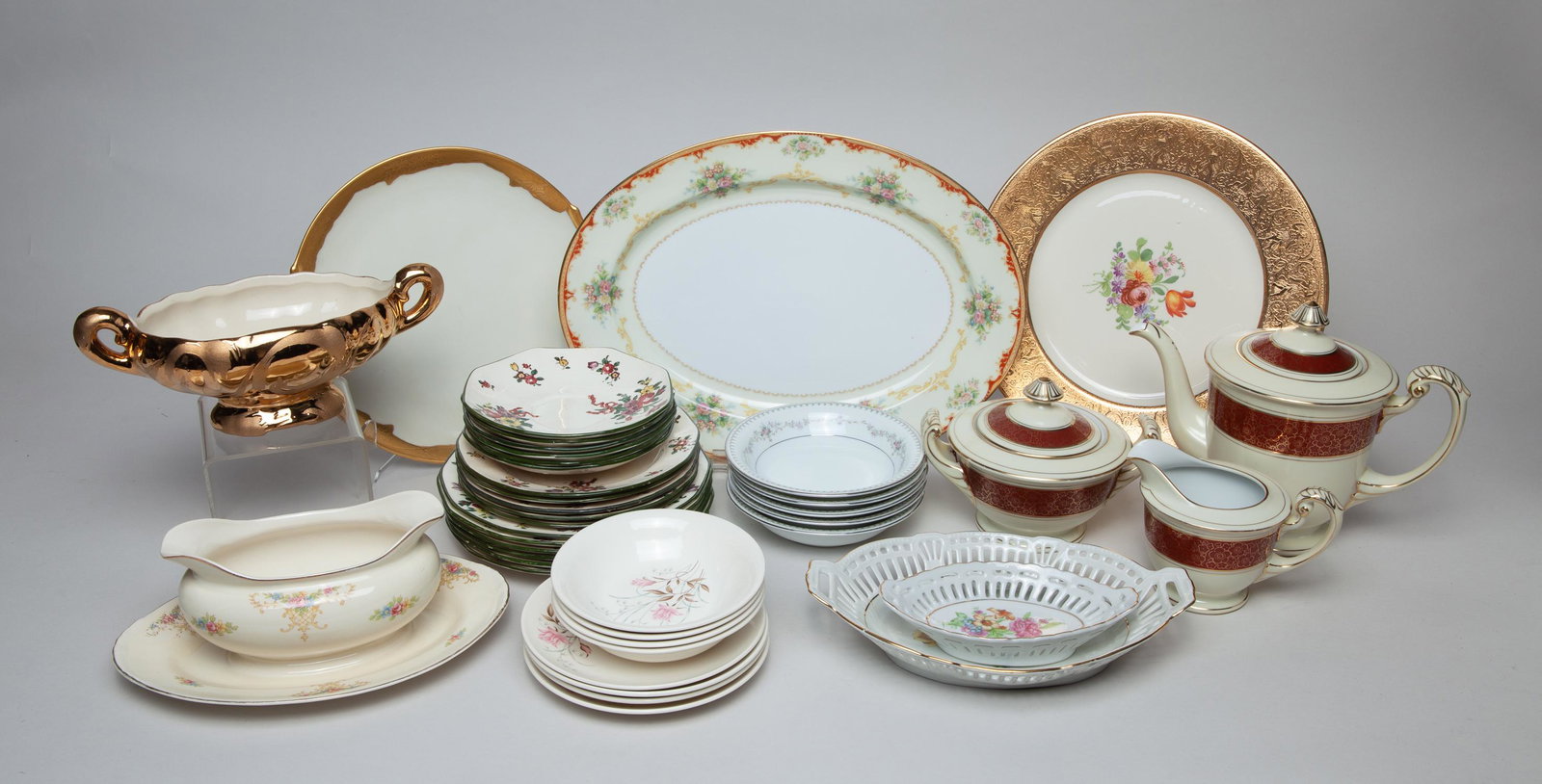 Collectible Porcelain Service Set: A large group of porcelain centerpieces, plates, bowls and a tea set, decorated with classical flower motif. 13.6inch L, 10.1inch W (largest).