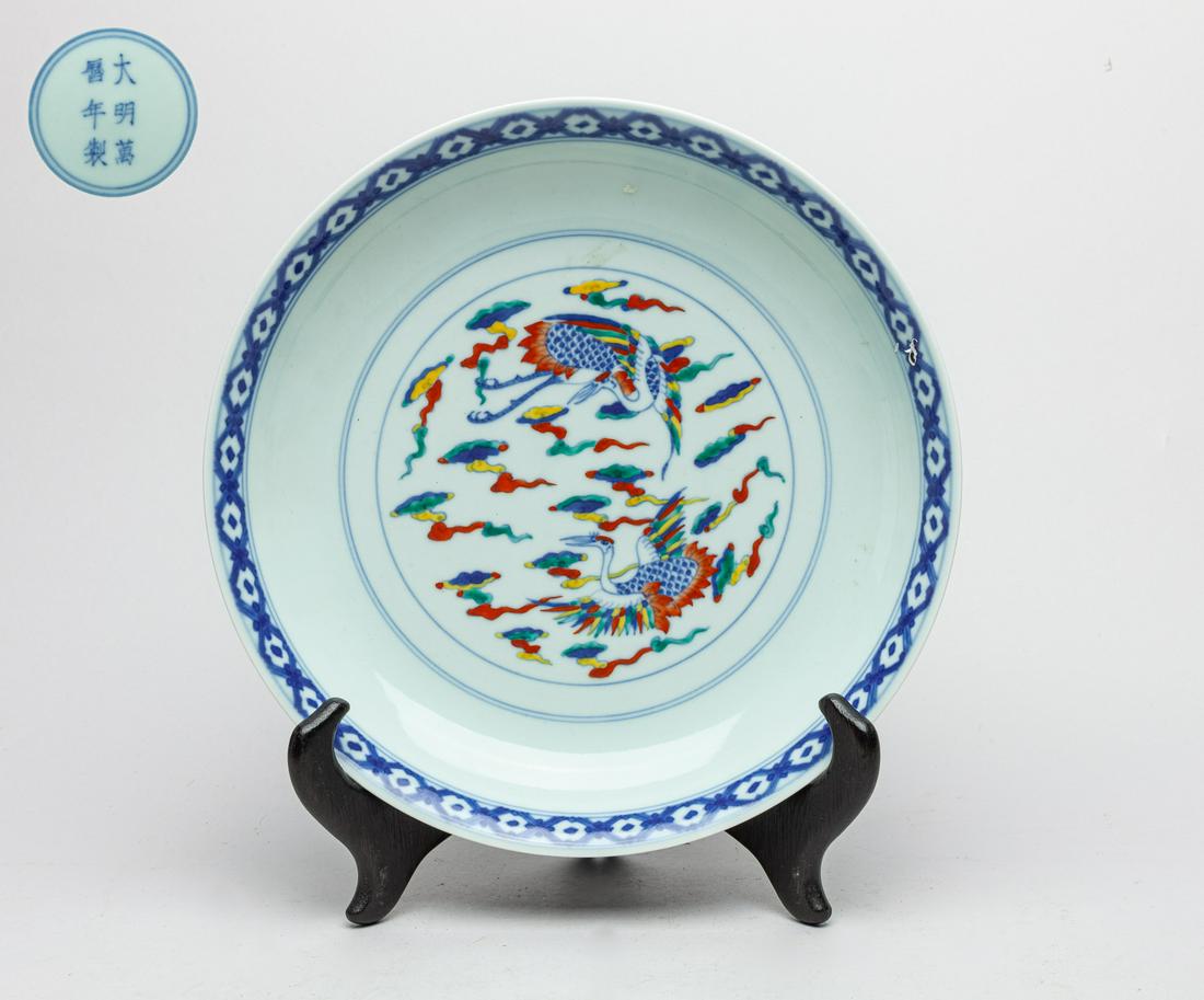 Collectible Chinese Douchai Porcelain Crane Plate: The interior center panel painted with a pair of cranes among clouds, the side with eight diagram patterns above sea waves, the base marked with six characters enclosed in double circles, with wood st