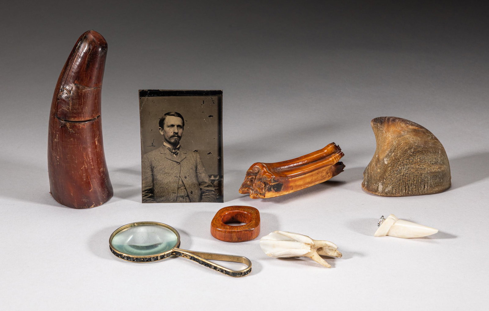Explorer's Collection of Horn Carvings: Including two horn table sculptures, three animal tooth sculptures, a bone like ring, a magnifying glass and a vintage tintype photo. 5inch H, 2.1inch L, 1.8inch W (largest).