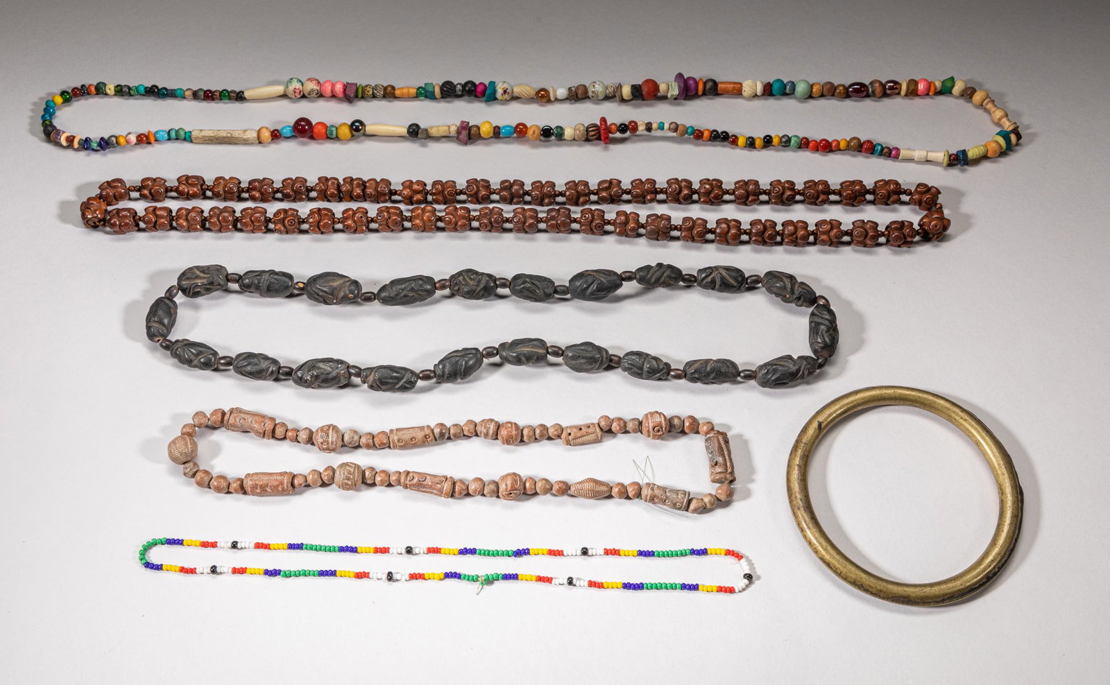 African Old Tribe Trade Necklace & Bangle: Including a large brass bangle and five trade bead necklaces, comprised of clay, wood, glass, stone and decor beads. 46inch L (largest).