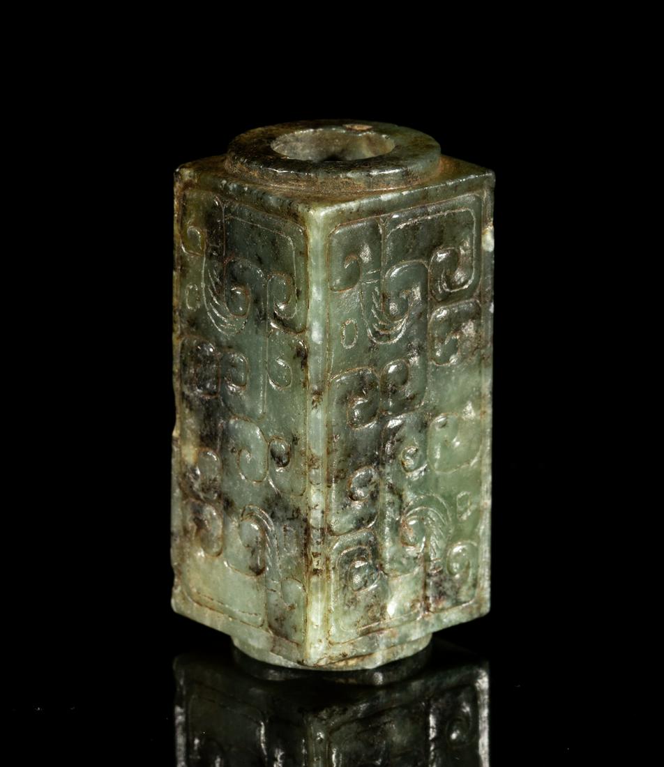 Chinese Russet Jade Toggle: Of cylindrical forms with square projections on four corners, each side carved with a pair of stylized archaistic dragons, the stone in mottled celadon tone. 2.18inch L, 1inch W. The Estate of Louis H