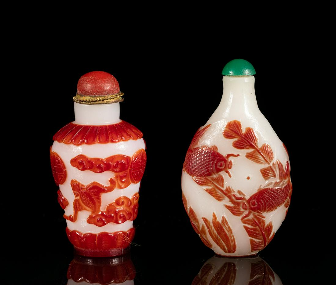 Chinese Overlay Glass Snuff Bottle: One of flattened oval form carved with a pair of fish amidst water plants on both sides, the other of ovoid vase form, carved with bats, shou characters and clouds between petal bands, all in red tone