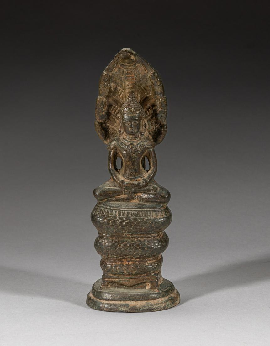 Antique Thailand Bronze Buddha: Cast seated in paryankasana on a tall stand surrounded with a coiled snake, the snake head stretching behind the Buddha head and carved with a flower, the hands held in dhyana mudra, 2.25inch L, 1.8in