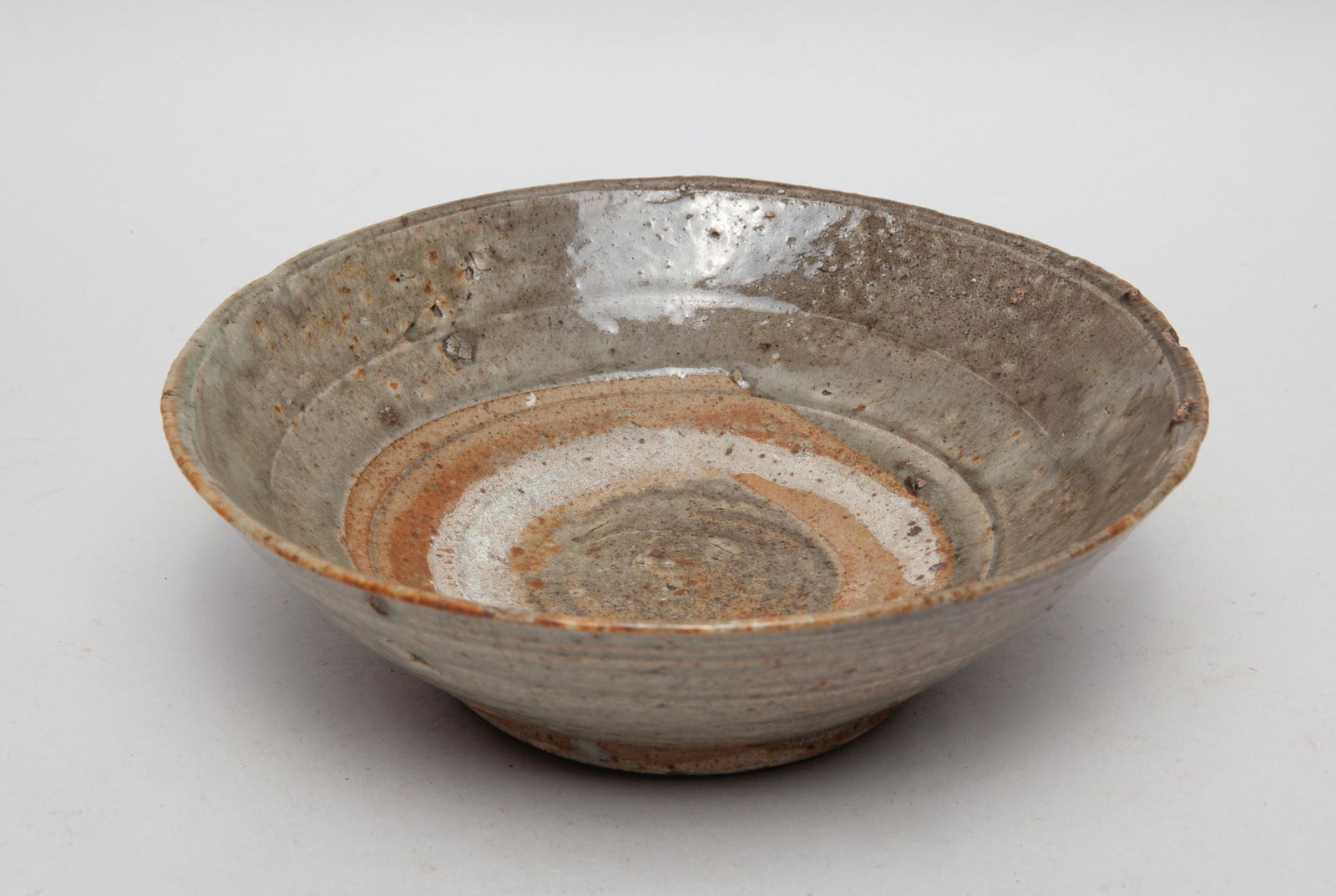 Antique Korean Celadon Bowl: Of circular form, applied with a mottled celadon glaze at the inside and out. 7.1inch W, 2.1inch H.