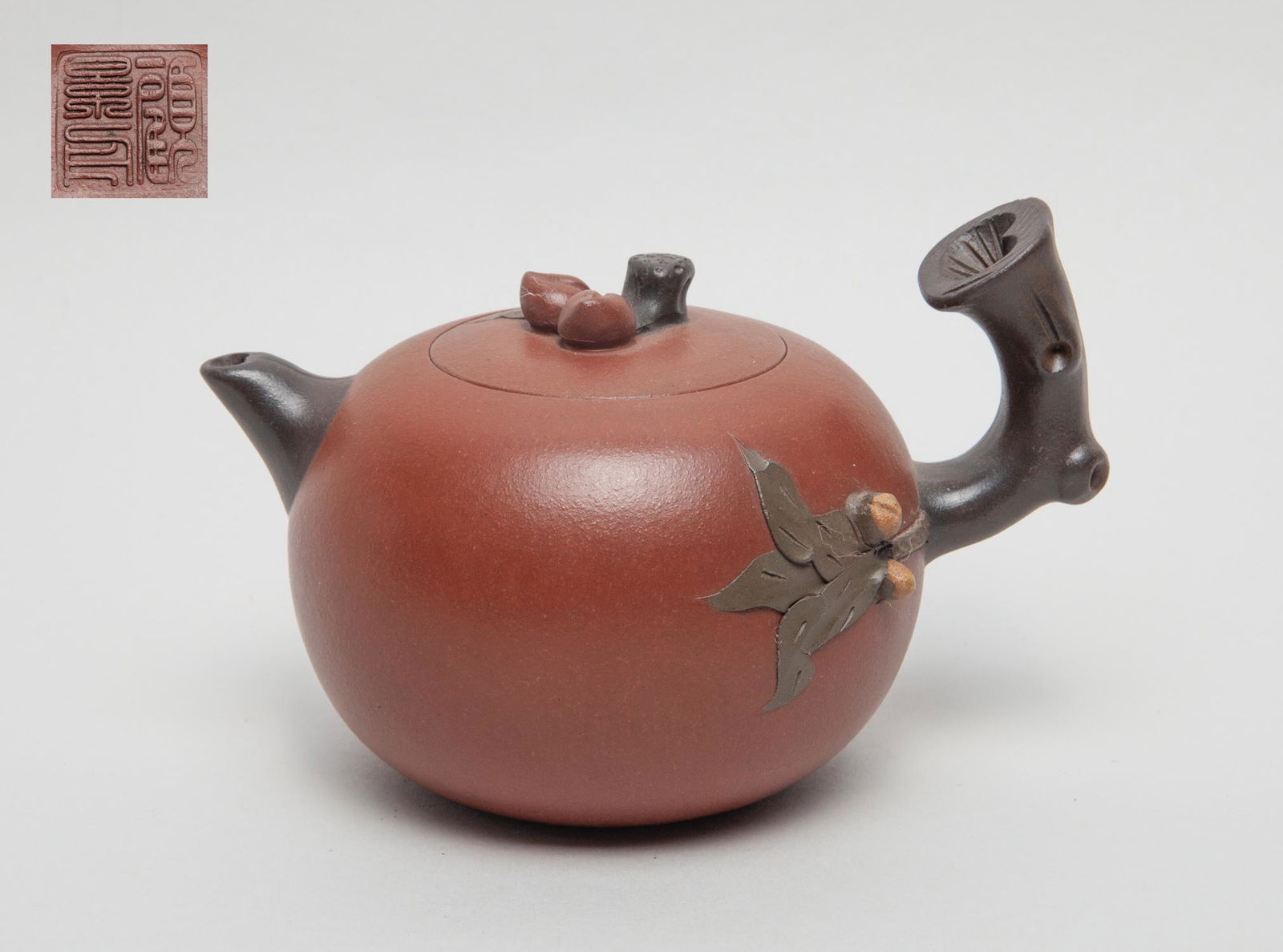Vintage Chinese Zisha Tea Pot: The compressed body set with a gnarled branch handle issuing leaves and peaches along the body, the cover with peach branch finial and the inside with a mark, the bottom with a seal mark. 6inch L, 4.3