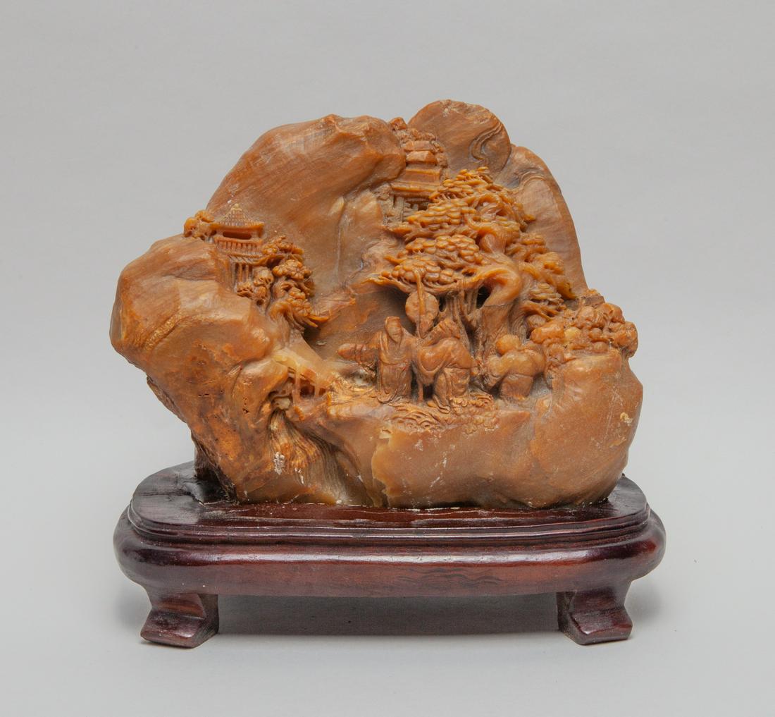 Large Chinese Soap Stone Sculpture: The irregular stone carved in multiple layers of relief with three figures in landscape with pavilions, trees and rock, the stone in a streaked russet tone. Approx. 6.6inch H, 8inch L, 4.2inch W (w/o 