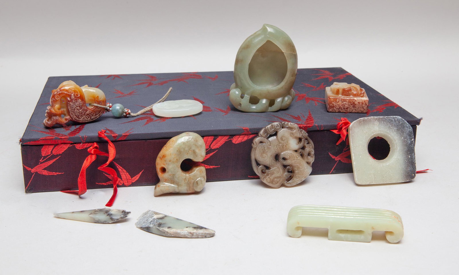 Estate Chinese Jade Toggles: Group of ten jade carvings, including a peach form washer, a seal, a pig-dragon toggle, an ax type toggle, a square toggle pierced at the centre, a buckle, a pendant carved as a sinuous beast and its 