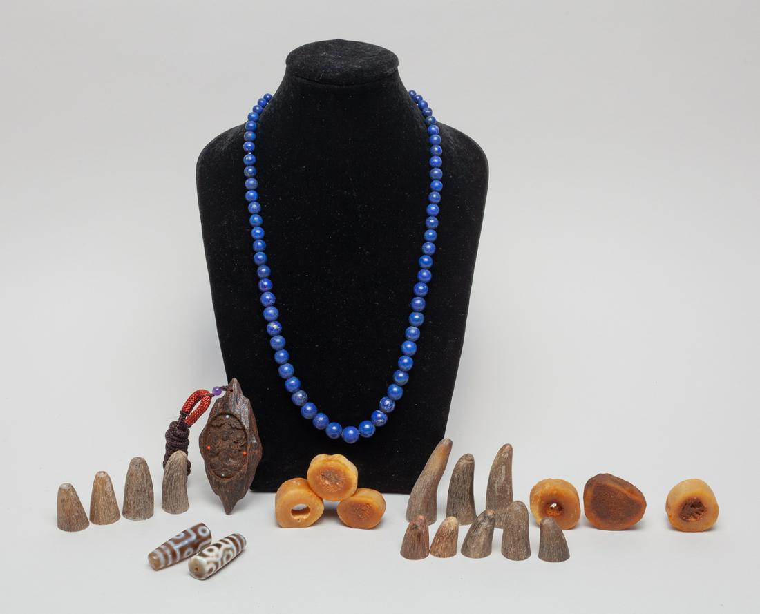 Tibetan Agarwood, Lapis & Dzi Beads: Including an agarwood toggle carved with seated Buddha, a lapis bead necklace, two dzi beads, and a large group of bone like carvings. 3.4inch L, 1.7inch W (agarwood size).