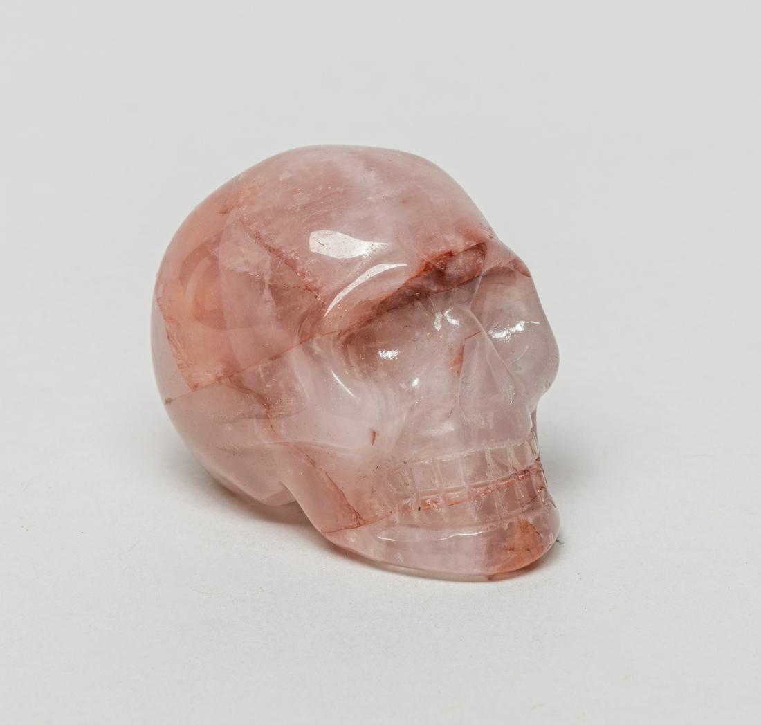Collectible Crystal Skull Sculpture: Collectible pink crystal skull sculpture with reddish streaks, the surface finely smoothed and polished. 1.9inch L, 1.4inch W, 1.4inch H.