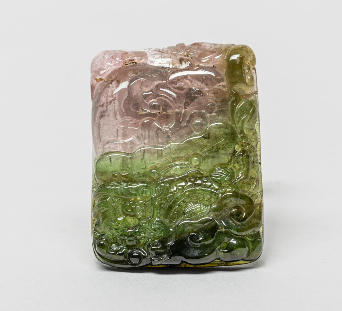 Special Color Chinese Tourmaline Pendant: Of rectangular form, one side skillfully carved with a dragon amid clouds and beneath ruyi and bats, the verso incised in low relief with ruyi, lotus leaf and coin, the stone of a variegated pink and 